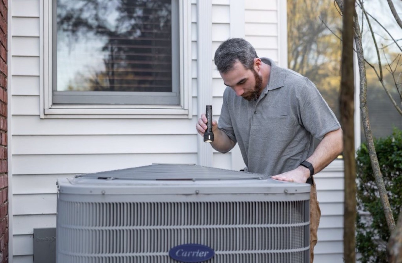 Technician inspecting a high-efficiency outdoor HVAC unit